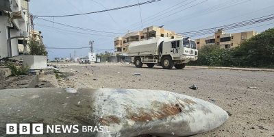 Legenda da foto, Forças de segurança da ONU baseadas no Líbano (Unifil) passam pelos restos de...